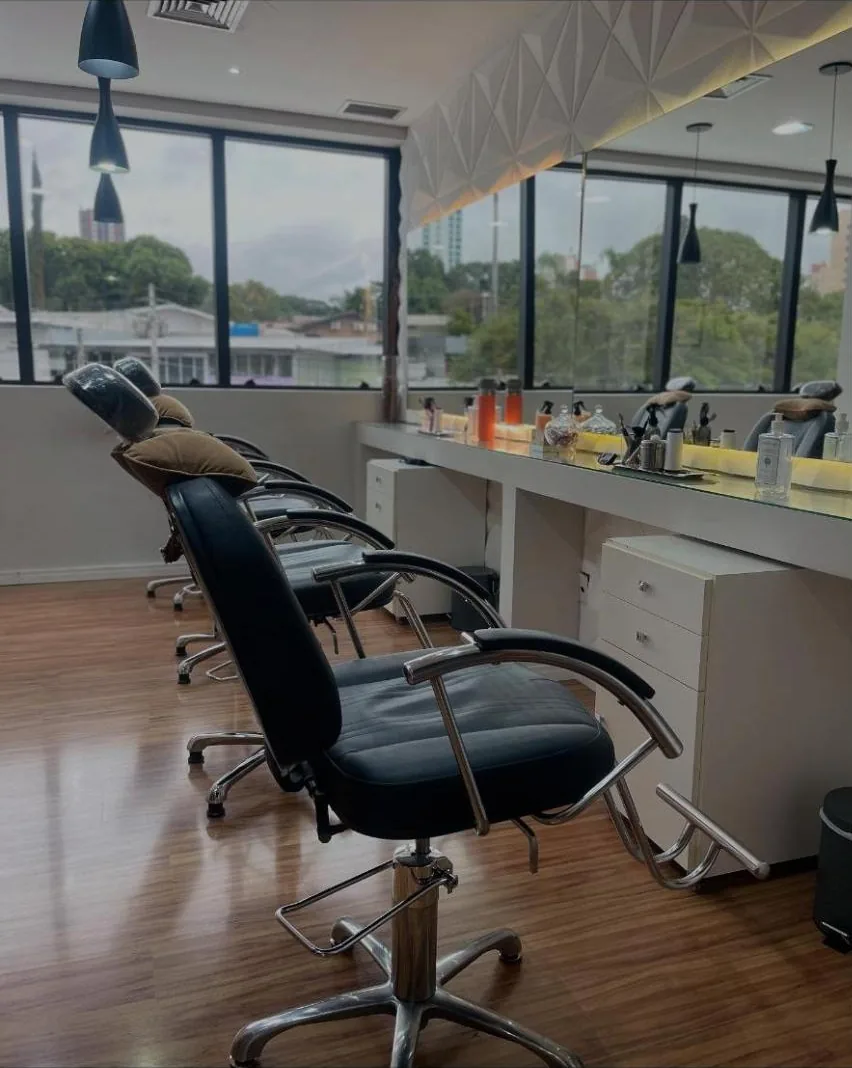 Sala de atendimento do Studio Barroso com cadeiras pretas, bancada iluminada e janelas para a rua